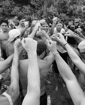Arms and hands from all sides meeting in the middle of a huddle, photographed from inside it